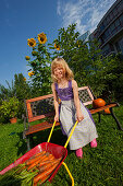 Girl harvesting carrots, pushing a wheelbarrow, Urban Gardening, Urban Farming, Stuttgart, Baden Wurttemberg, Germany