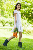 Young woman holding bunch of carrots