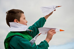 Boy playing with paper airplanes at seaside