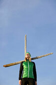 Young woman standing at a cross on a summit in the mountains, See, Tyrol, Austria