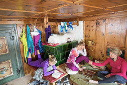 Drei junge Frauen entspannen nach dem Skifaren in einer gemütlichen Hütte, See, Tirol, Österreich