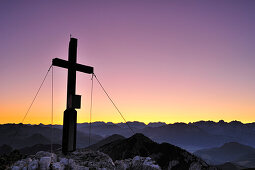 Cross at summit of Soinwand with Chiemgau range and Berchtesgaden range at dawn, view from Wendelstein range, Bavarian alps, Upper Bavaria, Bavaria, Germany, Europe