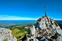 Mountaineers near summit cross, Kampenwand, lake Chiemsee in background, Chiemgau, Upper Bavaria, Germany