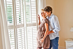 Pregnant women and young man looking out of the window, Hamburg, Germany