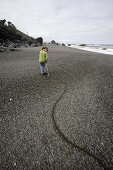 Young Girl Dragging Stick Along Sandy Beach, Redwood National Park, California, USA