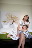 Mother and daughter sitting on a hotel bed, Fincken, Mecklenburg-Western Pomerania, Germany