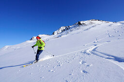 Woman descending through powder snow from Nadernachjoch, backcountry skiing at Nadernachjoch, Kitzbuehel Alps, Tyrol, Austria