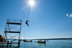 Kind springt von Sprungturm in Starnberger See, Oberbayern, Deutschland, Europa