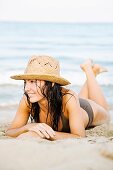 Portrait of a beautiful brunette woman at the beach with a bikini and a hat
