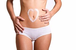 Woman drawing a heart in her belly with cream