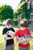 Zwei Jungen mit Kaninchen auf den Armen, Haus Strauss, Bauernkate in Klein Thurow, Roggendorf, Mecklenburg-Vorpommern, Deutschland