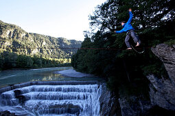 Young man balancing on a highline over a stream, Fuessen, Bavaria, Germany, Europe