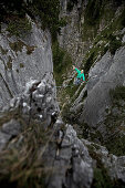 Junger Mann balanciert über eine Highline zwischen zwei Felsen, Oberammergau, Bayern, Deutschland, Europa