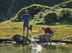 Hikers at Giglachsee lake skimming stones, Schladminger Tauern, Steiermark, Austria