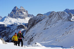 Junge Frau und junger Mann steigen auf Skitour zum Corno d'Angolo auf, Drei Zinnen im Hintergrund, Corno d'Angolo, Cortina, Venetien, Dolomiten, Italien, Europa