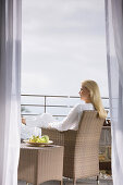 Blond woman sitting in an arm chair on the terrace