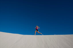 Young Woman Running over sand dunes. Young Woman Running over sand dunes.