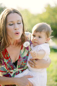 Young mother with her daugther, blowing dandelion clock, Old Danube, Vienna, Austria