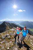 Young woman and young man hiking on ridge, Lake Achen in background, Unnutz, Brandenberg  Alps, Tyrol, Austria