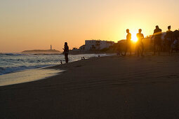 Menschen am Strand bei Sonnenuntergang, im Hintergrund das Cabo de Trafalgar, Los Canos de Meca, Andalusien, Spanien, Europa