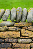 A close up of a traditional construction, a dry stone wall, with stones built up without mortar. Top stones places vertically., Detail of stone wall on Mainland Orkney Island in Scotland