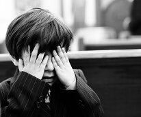 Young Boy in Suit Covering Eyes