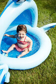 Young Girl in Red Bathing Suit Sitting in Small Pool