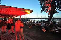 People dancing on the shore of lake Ammersee at sunset, Herrsching, Upper Bavaria, Germany, Europe