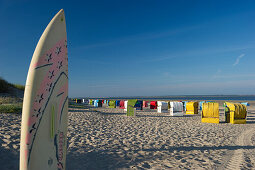 Colourful beachchairs and surfboard on the beach, Utersum, Foehr, North Frisian Islands, Schleswig-Holstein, Germany, Europe