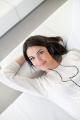 Pretty woman with headphones on the sofa