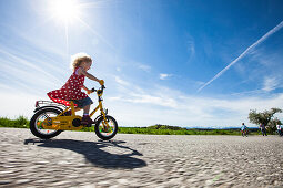 Kinder fahren Fahrrad, Eltern stehen im Hintergrund, Oberbayern, Bayern, Deutschland