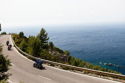 Three motor cyclists on winding coast road at Mediterranean Sea, Estellencs, Mallorca, Spain