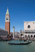 Gondoliere rowing gondola with tourists in front of Piazza San Marco with Campanile tower, Venice, Veneto, Italy, Europe