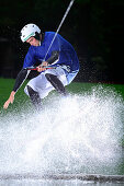 Young man surfing on a wakeboard, wakeboarding at lake Neubeurer See, Neubeuern, Rosenheim, Upper Bavaria, Bavaria, Germany