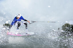 Young man surfing on wakeboard, wakeboarding at lake Neubeurer See, Neubeuern, Rosenheim, Upper Bavaria, Bavaria, Germany