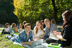 Group of young people learing at Dreisam riverbank, Freiburg im Breisgau, Black Forest, Baden-Wurttemberg, Germany