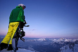 Snowboarder steht auf einem Berggipfel, Hahnenkamm, Tirol, Österreich