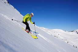 Female backcountry skier downhill skiing from Brechhorn, Kitzbuehel Alps, Tyrol, Austria