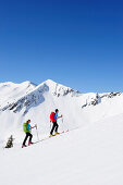 Two backcountry skiers ascending to Brechhorn, Grosser Rettenstein in background, Kitzbuehel Alps, Tyrol, Austria