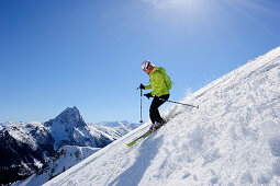 Female backcountry skier downhill skiing from mount Brechhorn, Grosser Rettenstein in background, Brechhorn, Kitzbuehel Alps, Tyrol, Austria