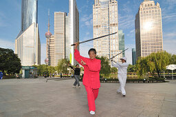 Older women practicing sword fighting techniques in Lujiazui Park, Oriental Pearl Tower, Pudong, Shanghai, China