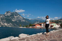 Young woman walking along the promenade of lake garda, Torbole, Riva del Garda, Lake Garda, Lago di Garda, Trient, Italy, Europe
