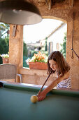 Girl playing billiards at a roofed terrace, Algaida, Mallorca, Balearic Islands, Spain