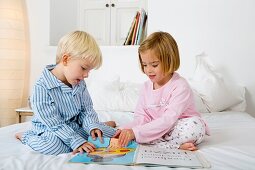Siblings reading a book in their pyjamas