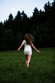 Young woman running over a meadow, Upper Bavaria, Germany