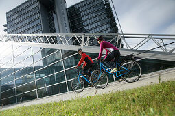 Couple riding e-bikes, Munich, Bavaria, Germany