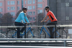Couple riding e-bikes, Munich, Bavaria, Germany