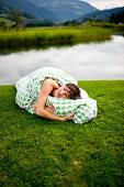 Frau liegt mit Kissen und Decke auf einem Golfplatz, Steiermark, Österreich