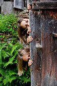 Zwei Mädchen hinter einer alten Holztür, Steiermark, Österreich