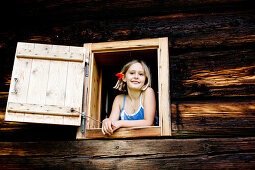 Mädchen schaut aus einem Fenster von einem Bauernhaus, Steiermark, Österreich